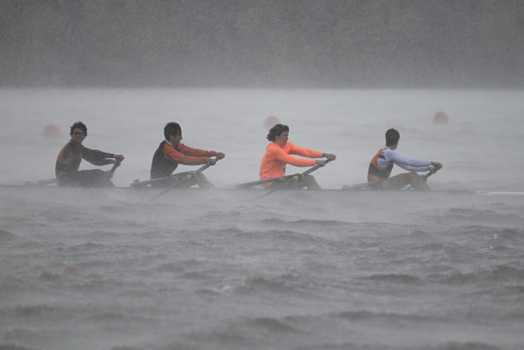 Northville Rowing battling heavy rain and rough water during a spring race, showcasing grit and teamwork.